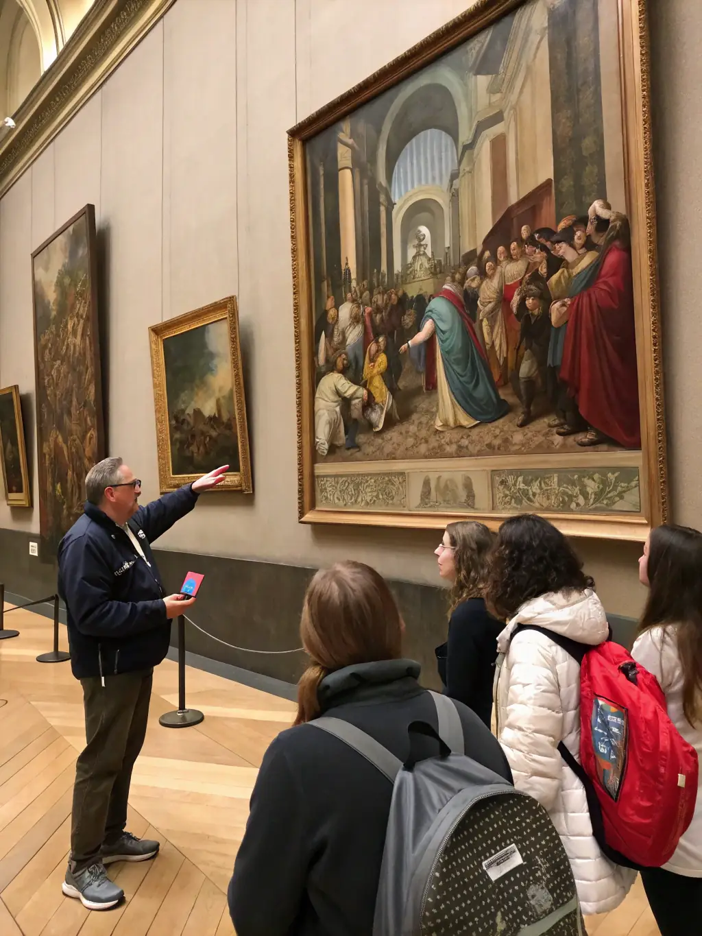 A photograph of an art mediator guiding visitors through an exhibition, explaining the context and significance of the artworks.